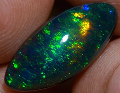 Opale noire captivante, variant de vert vibrant à bleu envoûtant, sa face arrière offre une brillance encore plus intense, agrémentée d'une pointe sombre