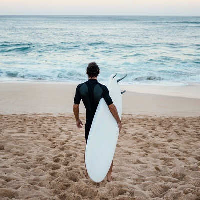 surfeur avec un longboard sous le bras sur la plage