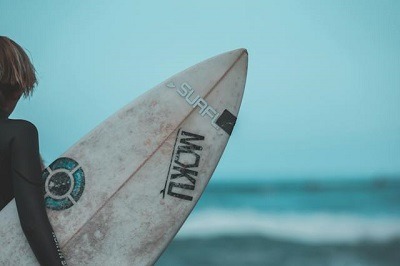 surfeur avec sa planche sou sle bras