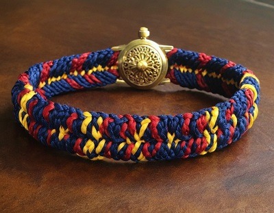 Bracelet Kumihimo avec des couleurs jaunes, rouge et bleu sur une table