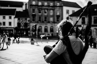 image en noir en blanc une personne jouant de la cornemuse dans la rue