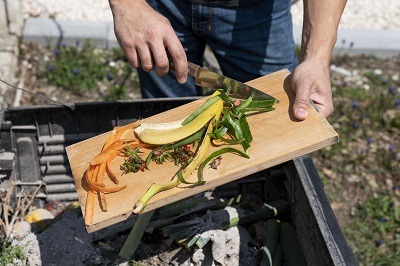 Choisir un composteur : Aide à la découverte de celui qui vous convient le mieux 2 personne jetant ses déchets de cuisine dans un composteur