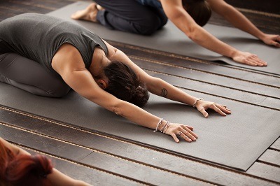 Groupe de jeunes sportifs pratiquant une leçon de yoga avec un instructeur, s'étirant dans l'exercice pour enfants, pose Balasana, s'entraîner, intérieur, studio, gros plan