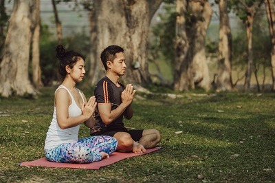Couple qui fait de la méditation dans un parc public