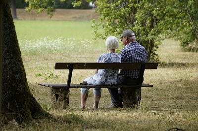 couple de retraités assis dans un jardin public sur un banc